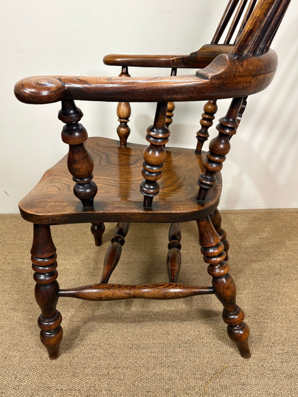 A 19th-century oak and elm Windsor armchair featuring a hoop back with spindles, a central pierced splat, turned arm supports, turned legs, and a saddle seat. View V