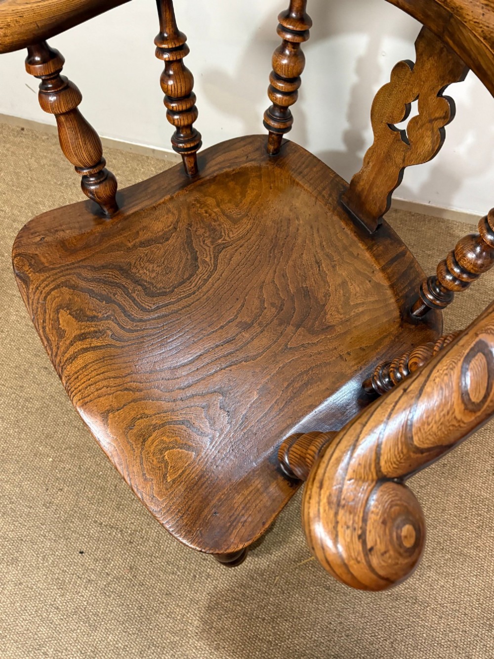 A 19th-century oak and elm Windsor armchair featuring a hoop back with spindles, a central pierced splat, turned arm supports, turned legs, and a saddle seat. View VI