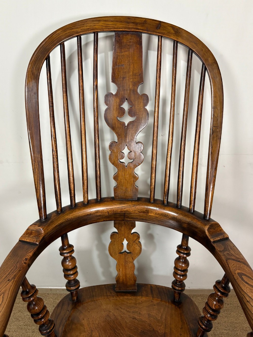 A 19th-century oak and elm Windsor armchair featuring a hoop back with spindles, a central pierced splat, turned arm supports, turned legs, and a saddle seat. View VII