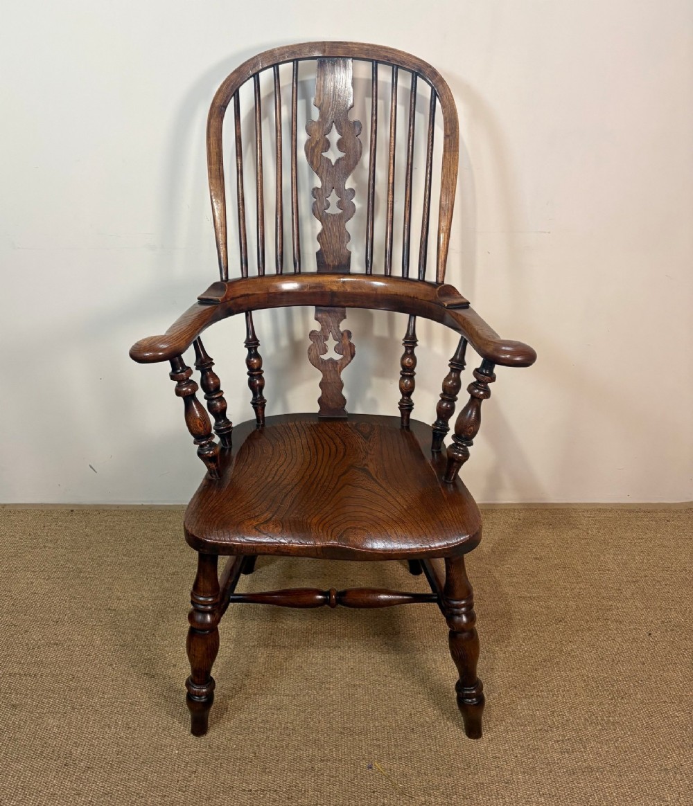 A 19th-century dark oak and elm Windsor armchair featuring a hoop back, central pierced splat, turned arm supports, and turned legs joined by stretchers. View II
