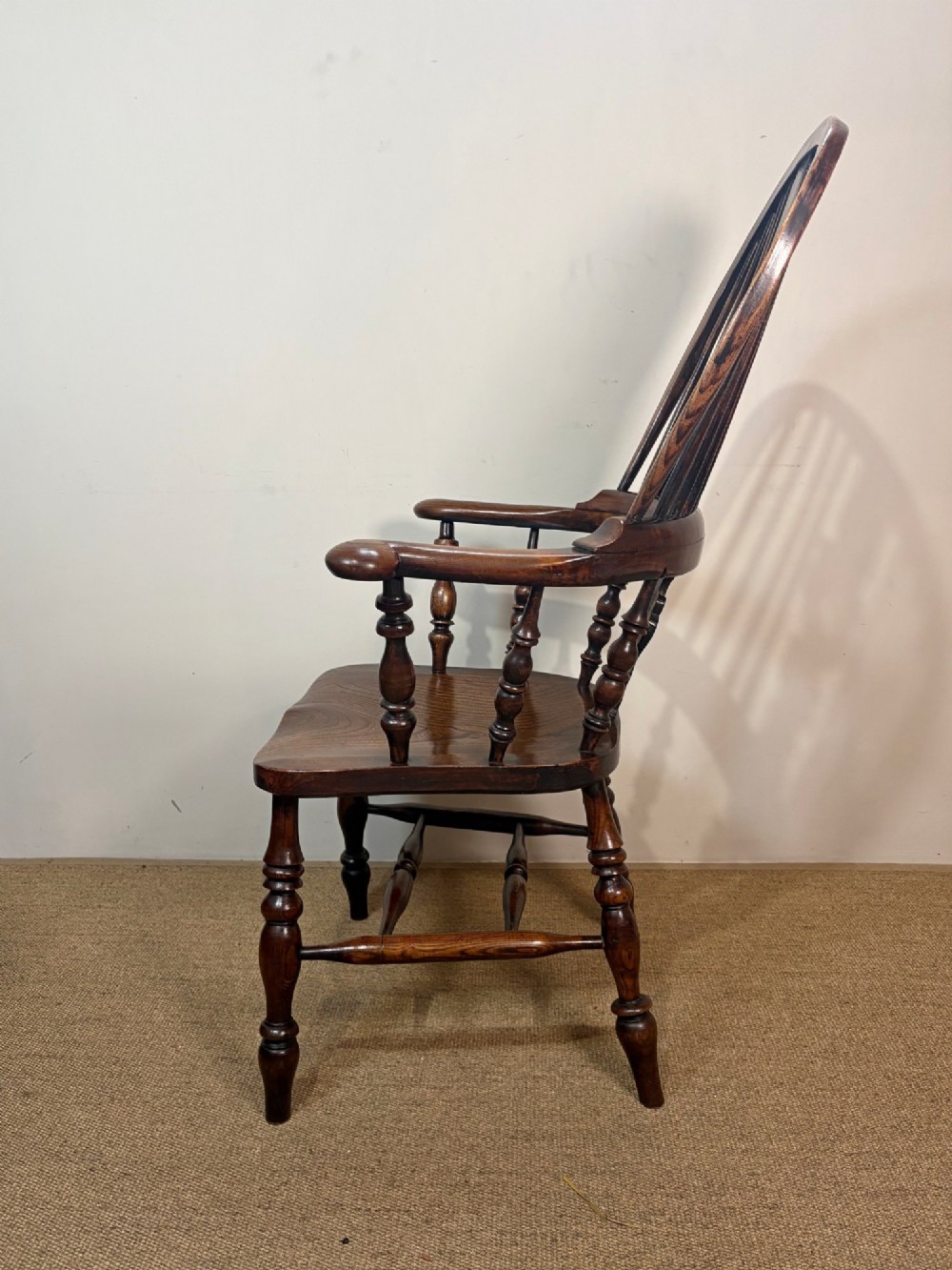 A 19th-century dark oak and elm Windsor armchair featuring a hoop back, central pierced splat, turned arm supports, and turned legs joined by stretchers. View III