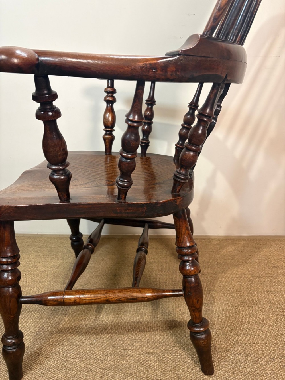 A 19th-century dark oak and elm Windsor armchair featuring a hoop back, central pierced splat, turned arm supports, and turned legs joined by stretchers. View IV