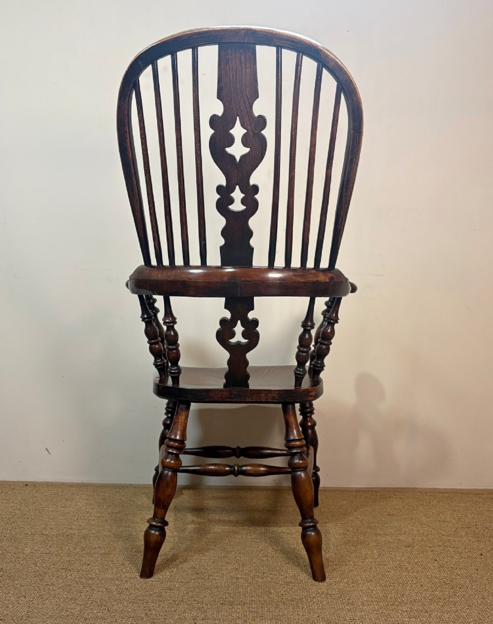 A 19th-century dark oak and elm Windsor armchair featuring a hoop back, central pierced splat, turned arm supports, and turned legs joined by stretchers. View V