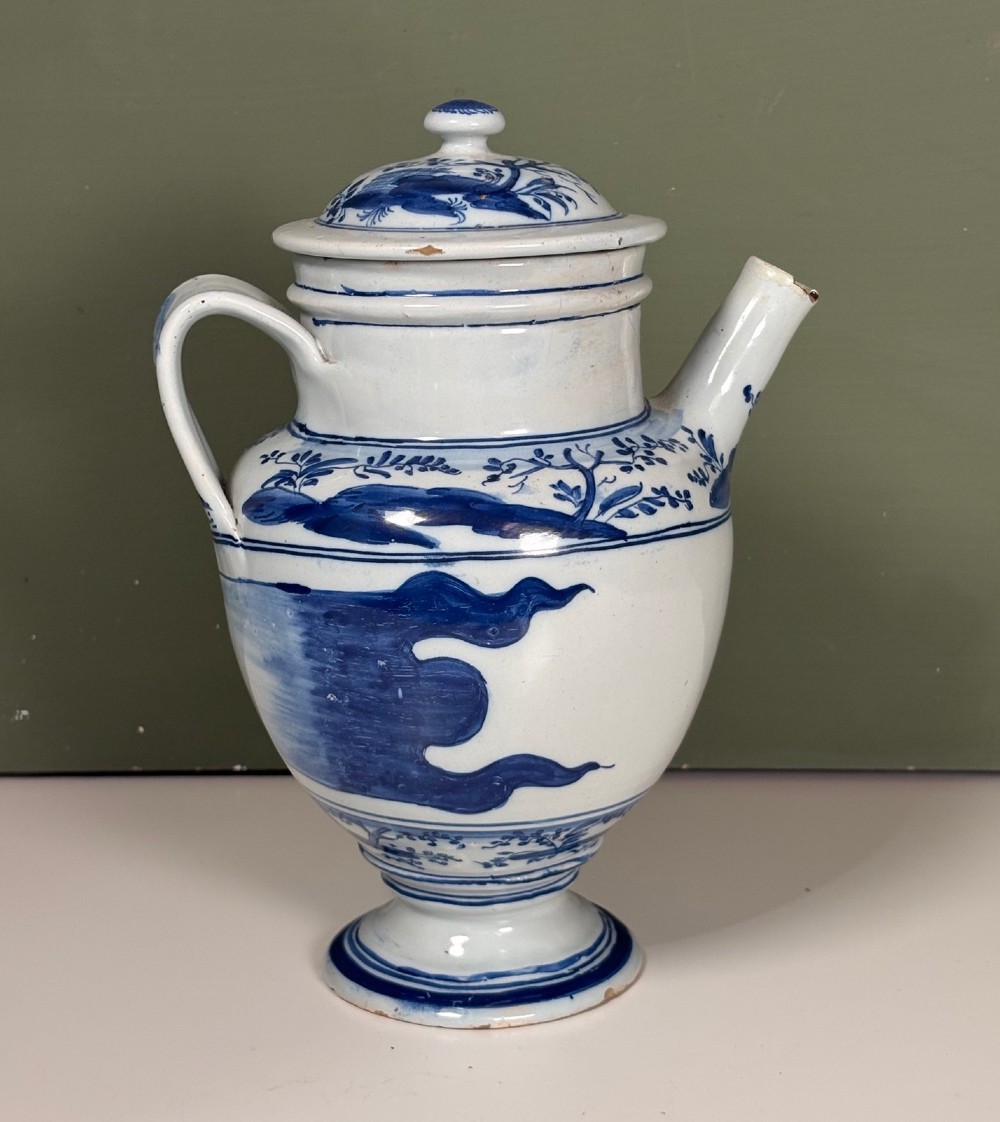 An 18th-century blue and white tin-glazed Delftware spouted apothecary jar featuring a fitted lid, side handle, and painted foliate decoration. View II