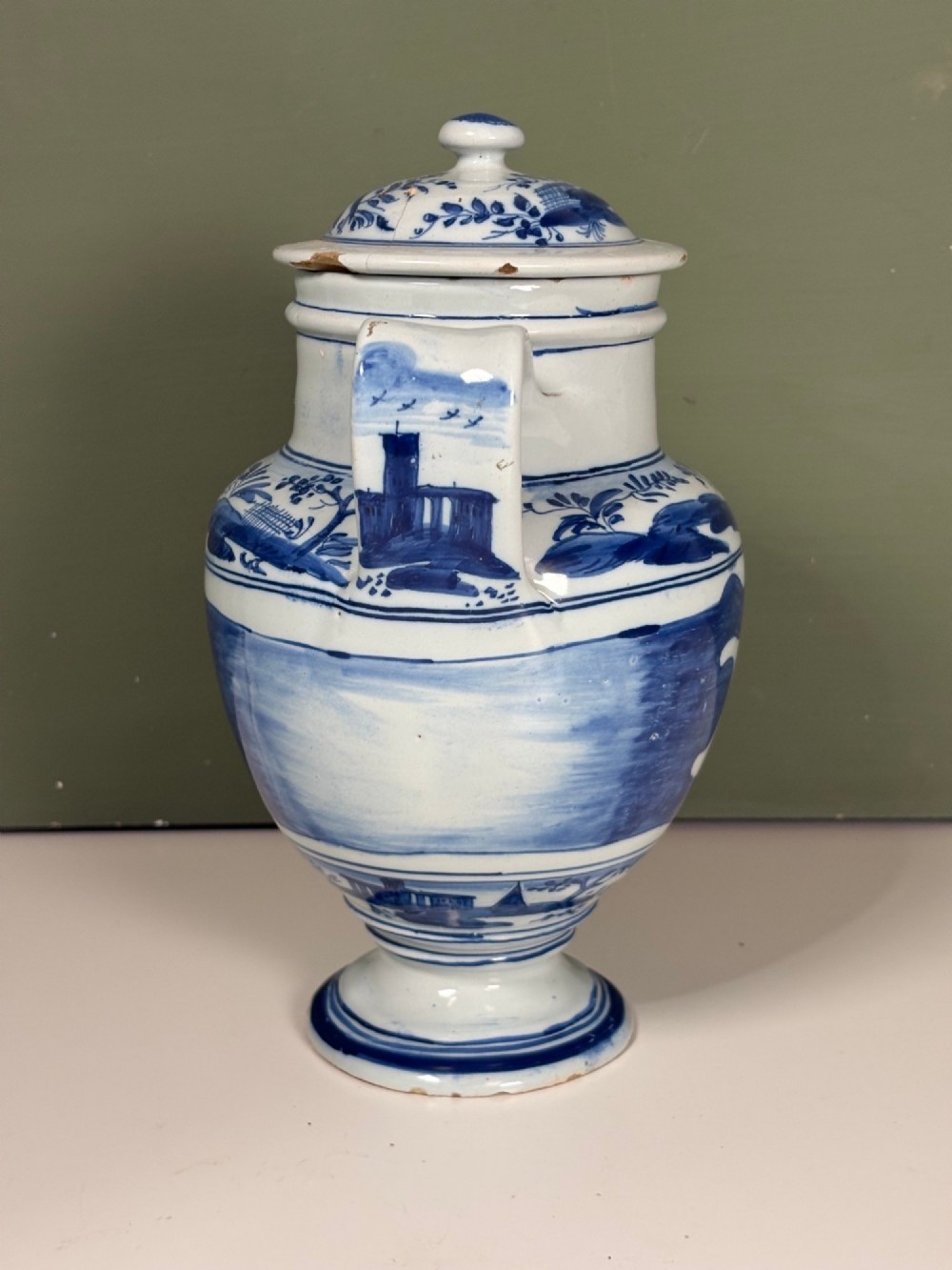 An 18th-century blue and white tin-glazed Delftware spouted apothecary jar featuring a fitted lid, side handle, and painted foliate decoration. View III