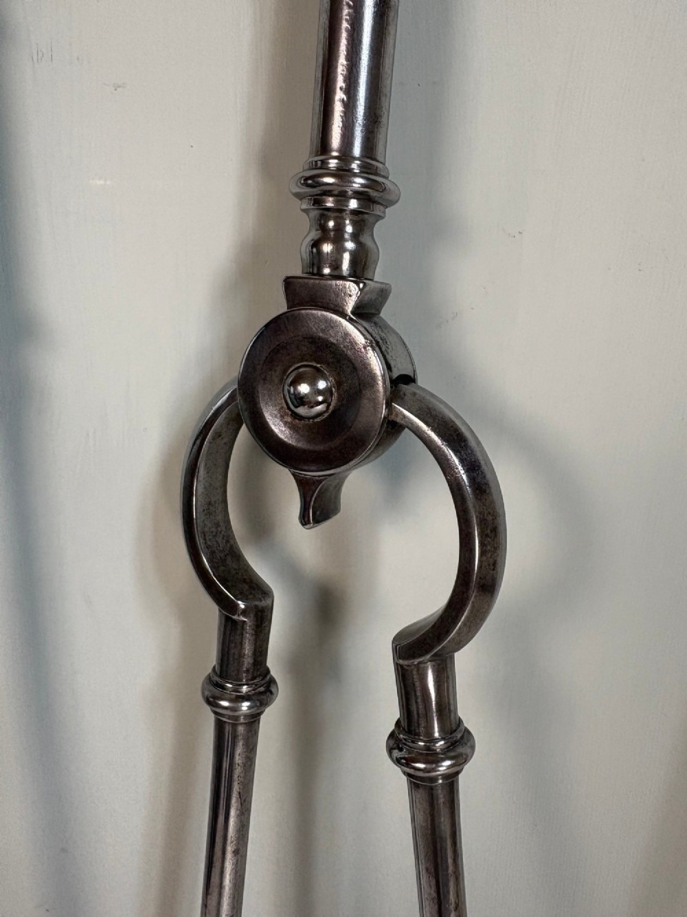 A set of three 18th-century steel fire tools, including a poker, tongs, and a pierced shovel, topped with decorative brass finials. View VI