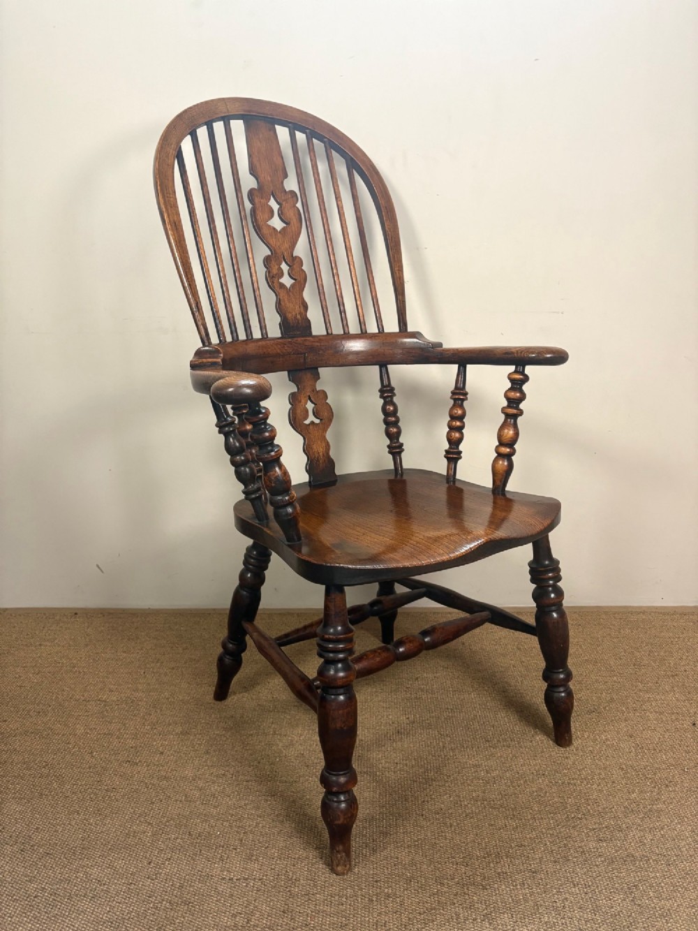 A 19th-century oak and elm Windsor armchair featuring a high hoop back, turned spindles, a pierced central splat, turned legs, and a solid saddle seat. View II