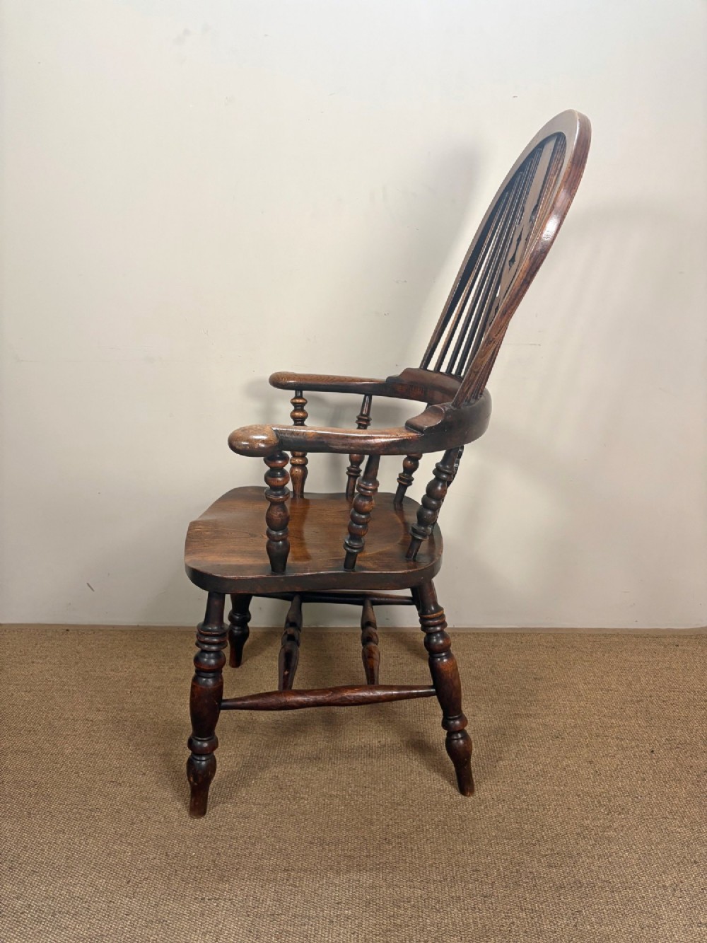 A 19th-century oak and elm Windsor armchair featuring a high hoop back, turned spindles, a pierced central splat, turned legs, and a solid saddle seat. View III
