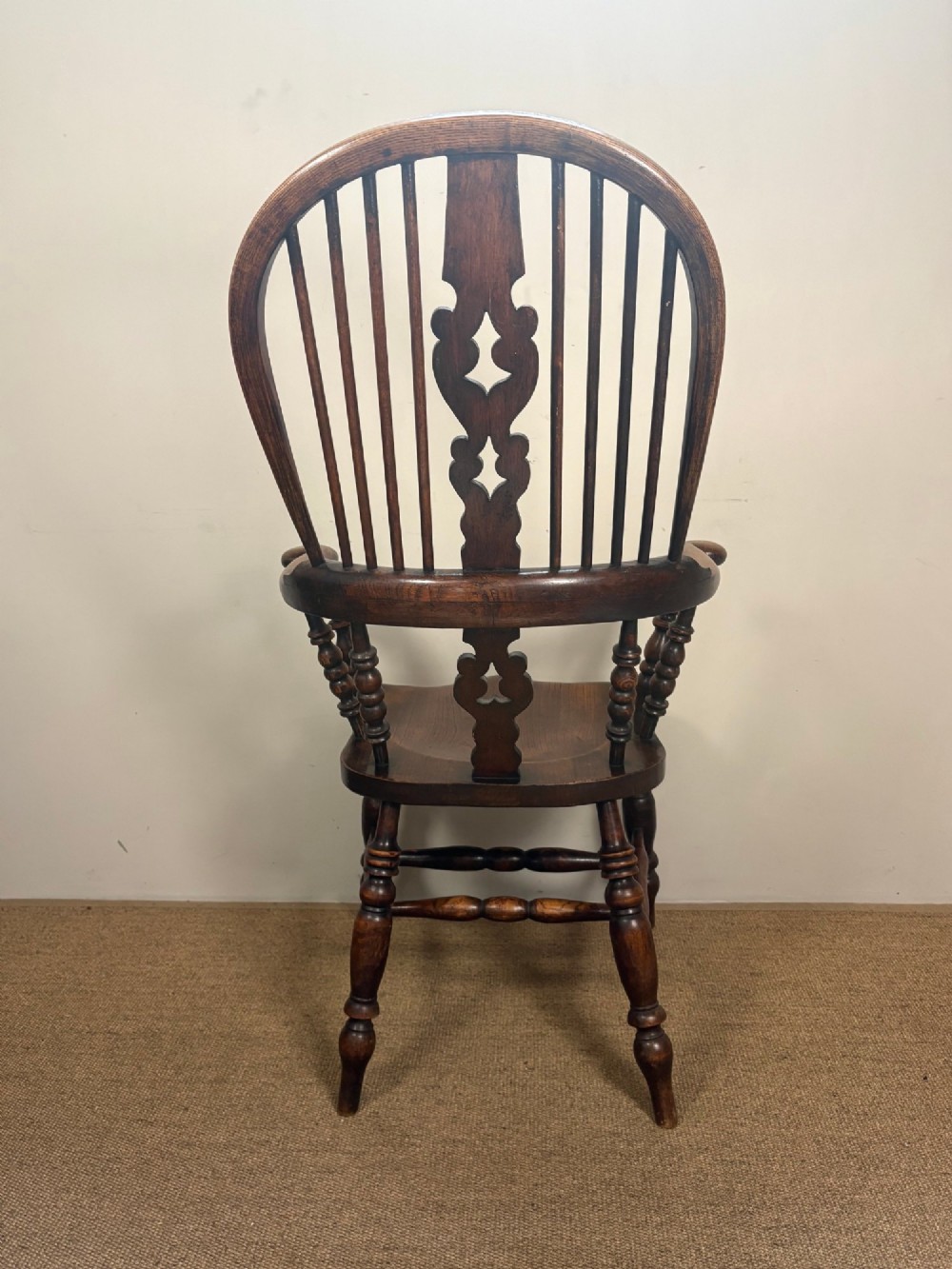 A 19th-century oak and elm Windsor armchair featuring a high hoop back, turned spindles, a pierced central splat, turned legs, and a solid saddle seat. View IV