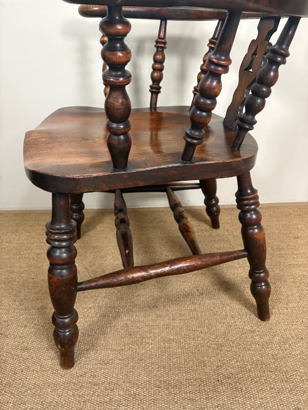A 19th-century oak and elm Windsor armchair featuring a high hoop back, turned spindles, a pierced central splat, turned legs, and a solid saddle seat. View VI