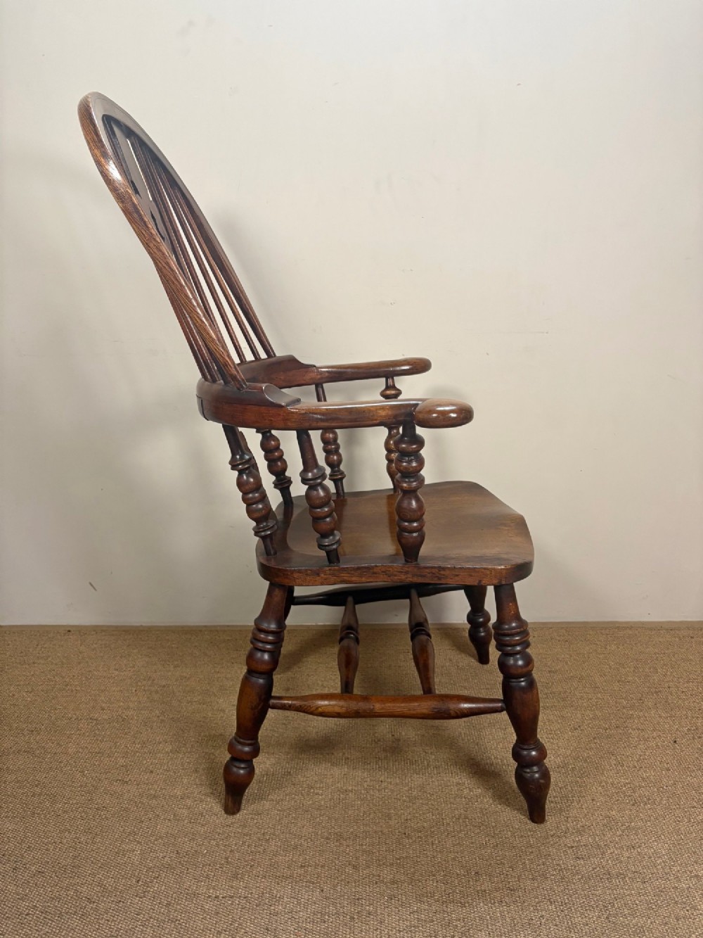 A nineteenth-century elm and beech Windsor armchair featuring a high hoop back, pierced central splat, turned spindles, curved armrests, and turned legs linked by an H-stretcher. View III