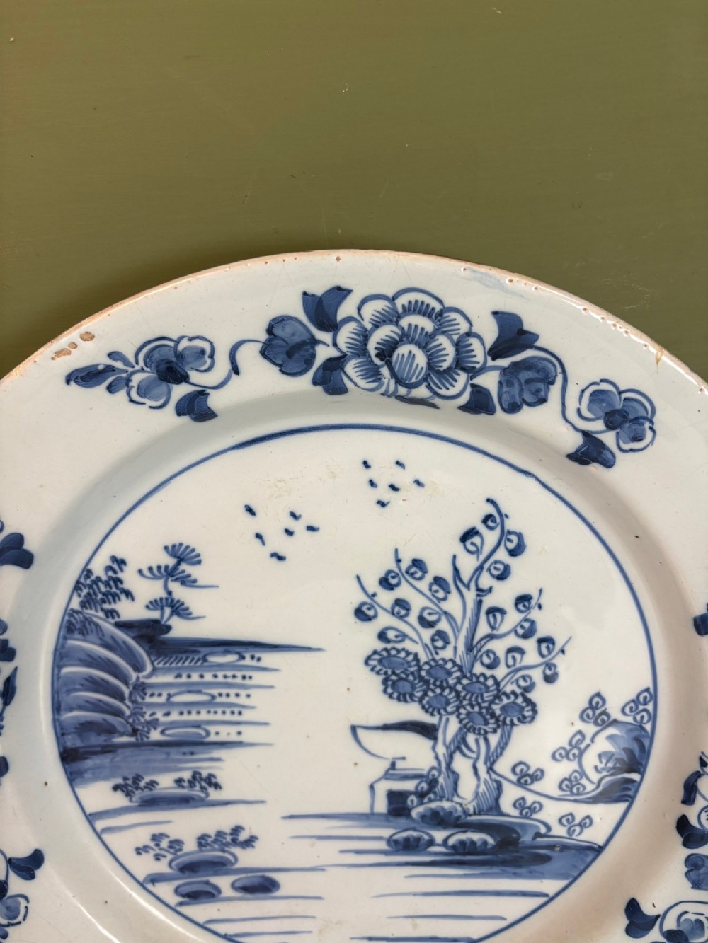 An 18th-century Dutch Delft tin-glazed earthenware charger featuring hand-painted cobalt blue floral motifs on the rim and a central chinoiserie landscape scene. View II