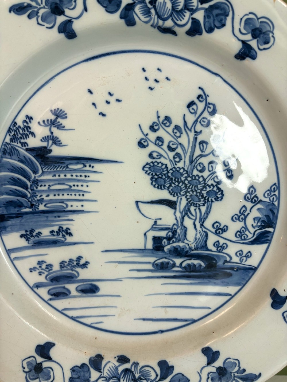 An 18th-century Dutch Delft tin-glazed earthenware charger featuring hand-painted cobalt blue floral motifs on the rim and a central chinoiserie landscape scene. View III