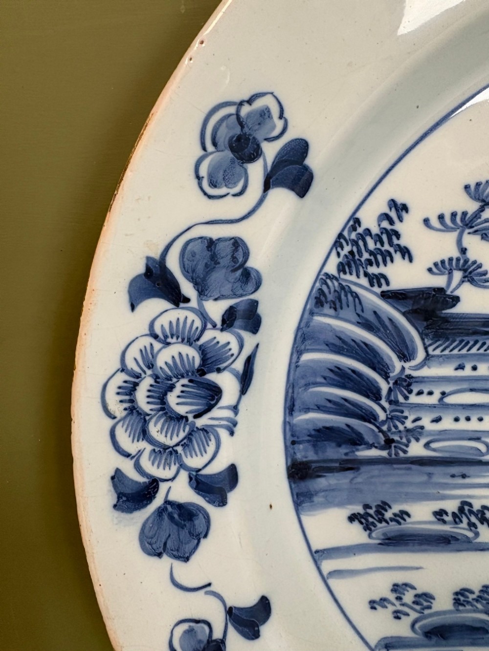 An 18th-century Dutch Delft tin-glazed earthenware charger featuring hand-painted cobalt blue floral motifs on the rim and a central chinoiserie landscape scene. View IV