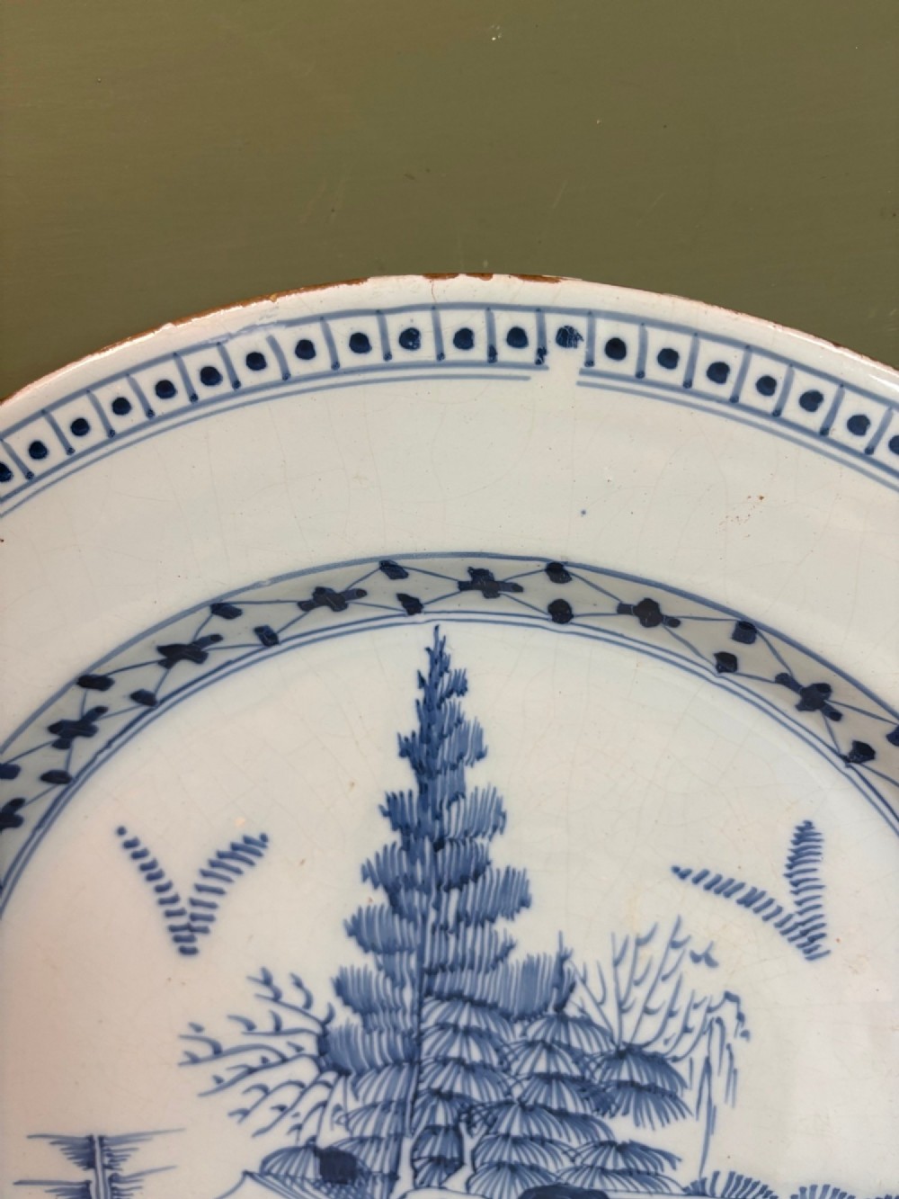 An 18th-century circular tin-glazed earthenware charger featuring hand-painted cobalt blue trees and geometric borders on a white ground. View II