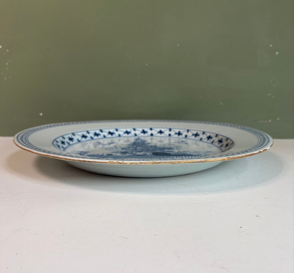 An 18th-century circular tin-glazed earthenware charger featuring hand-painted cobalt blue trees and geometric borders on a white ground. View IV