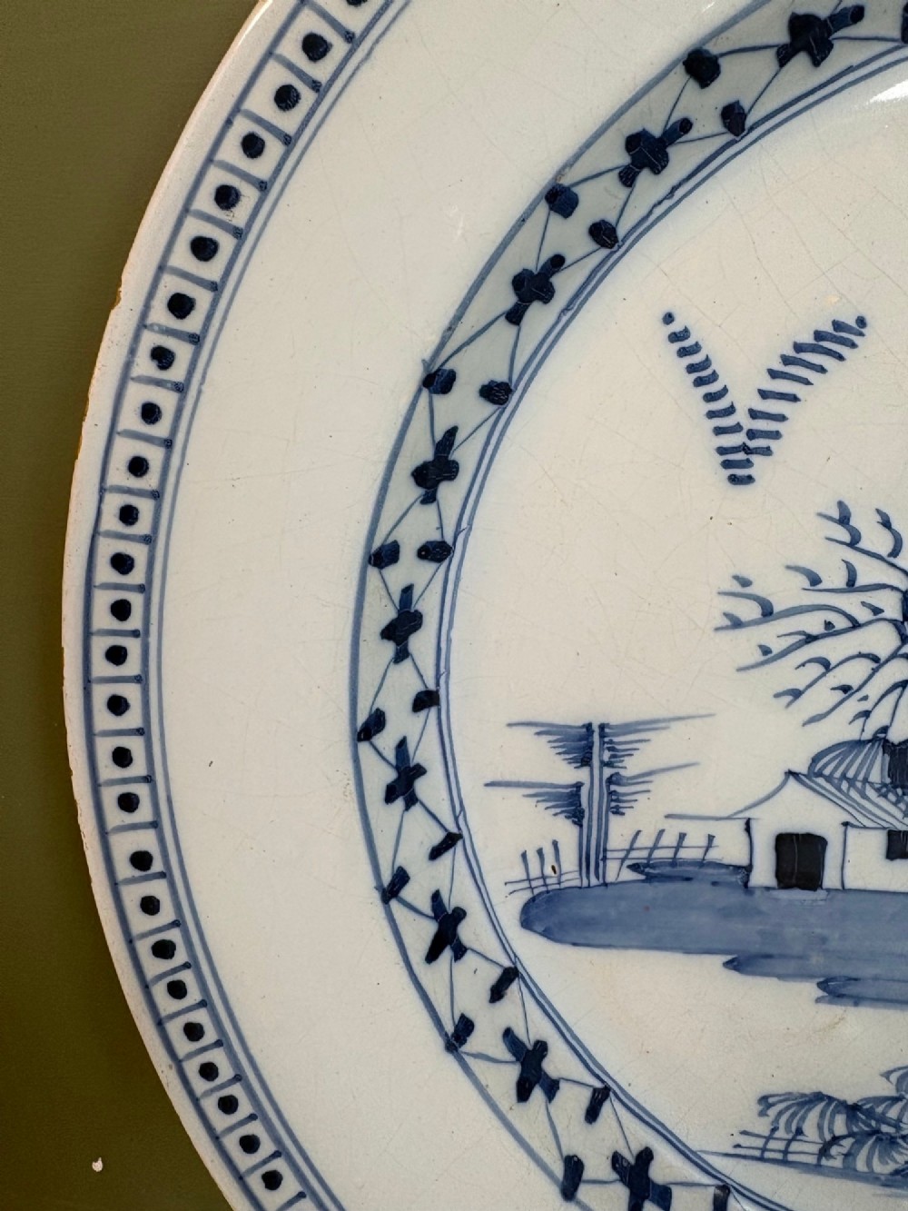 An 18th-century circular tin-glazed earthenware charger featuring hand-painted cobalt blue trees and geometric borders on a white ground. View V