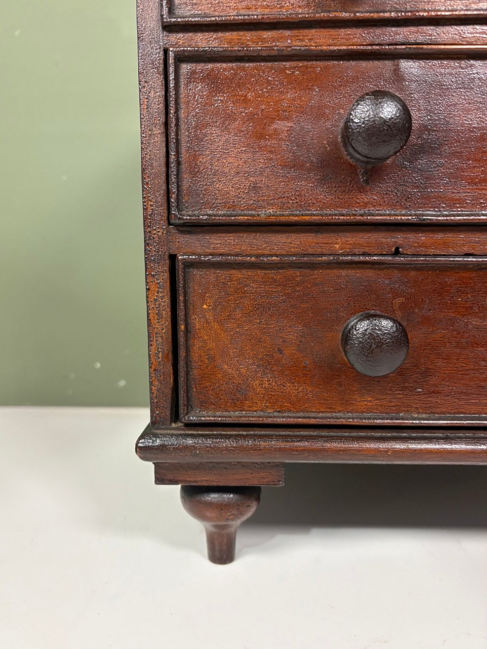 A 19th-century dark oak miniature chest featuring a hinged top lid opening to partitioned compartments filled with sea shells, above three drawers with turned wooden knobs. View VII