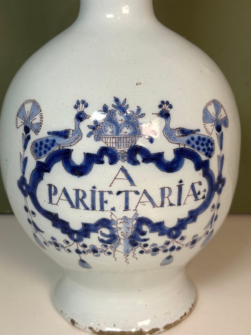 An 18th-century tin-glazed earthenware Delft apothecary bottle decorated with a hand-painted blue cartouche, peacocks, and Latin inscription. View II