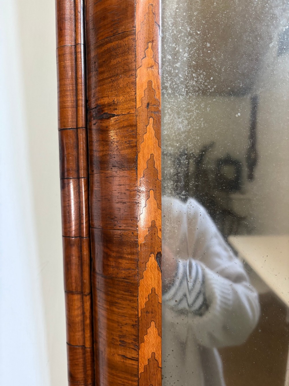 An 18th-century rectangular wall mirror featuring a cushion-moulded walnut frame with crossgrain veneers and herringbone inlay surrounding an aged reflective glass plate. View III
