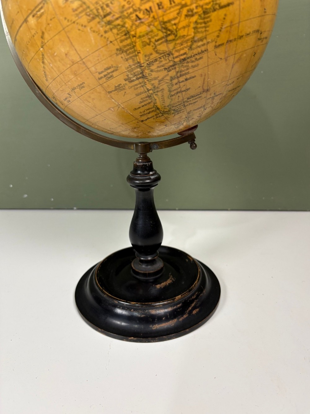 An antique terrestrial table globe with printed paper map gores, a brass semi-meridian arc, and a turned ebonised wooden base. View III