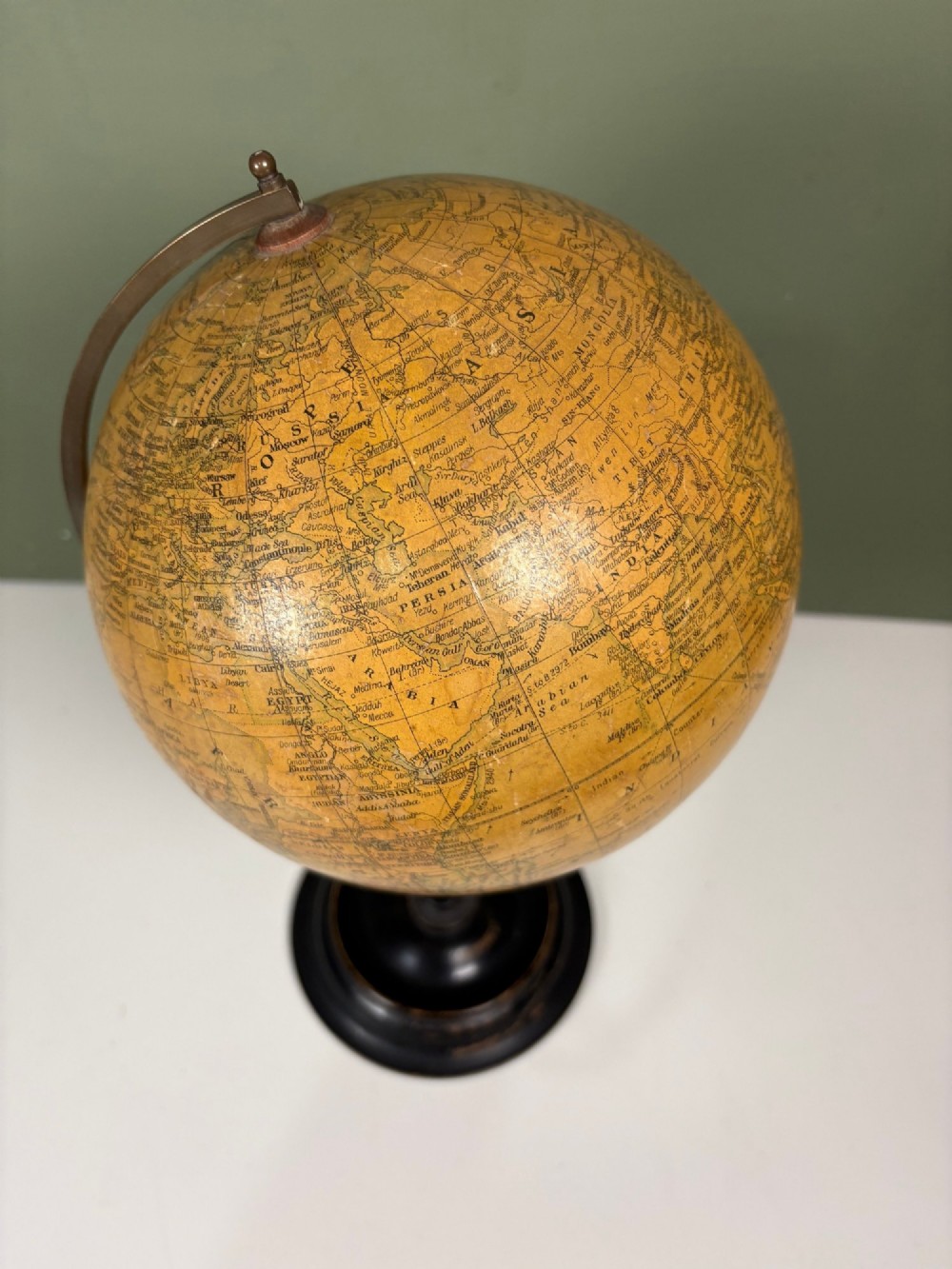 An antique terrestrial table globe with printed paper map gores, a brass semi-meridian arc, and a turned ebonised wooden base. View IV