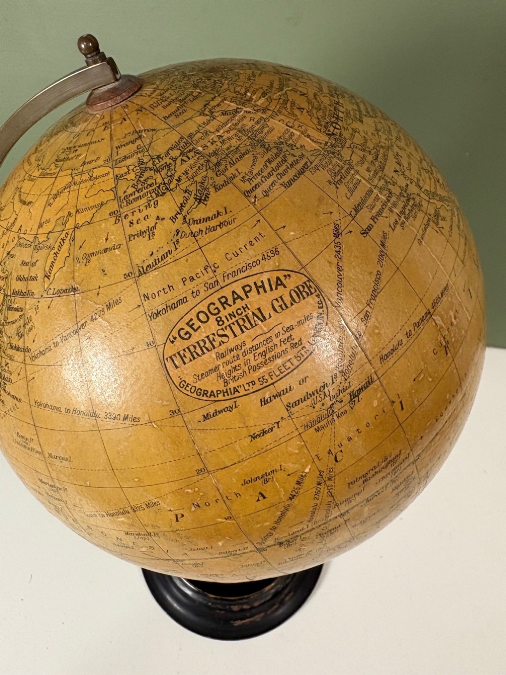 An antique terrestrial table globe with printed paper map gores, a brass semi-meridian arc, and a turned ebonised wooden base. View V
