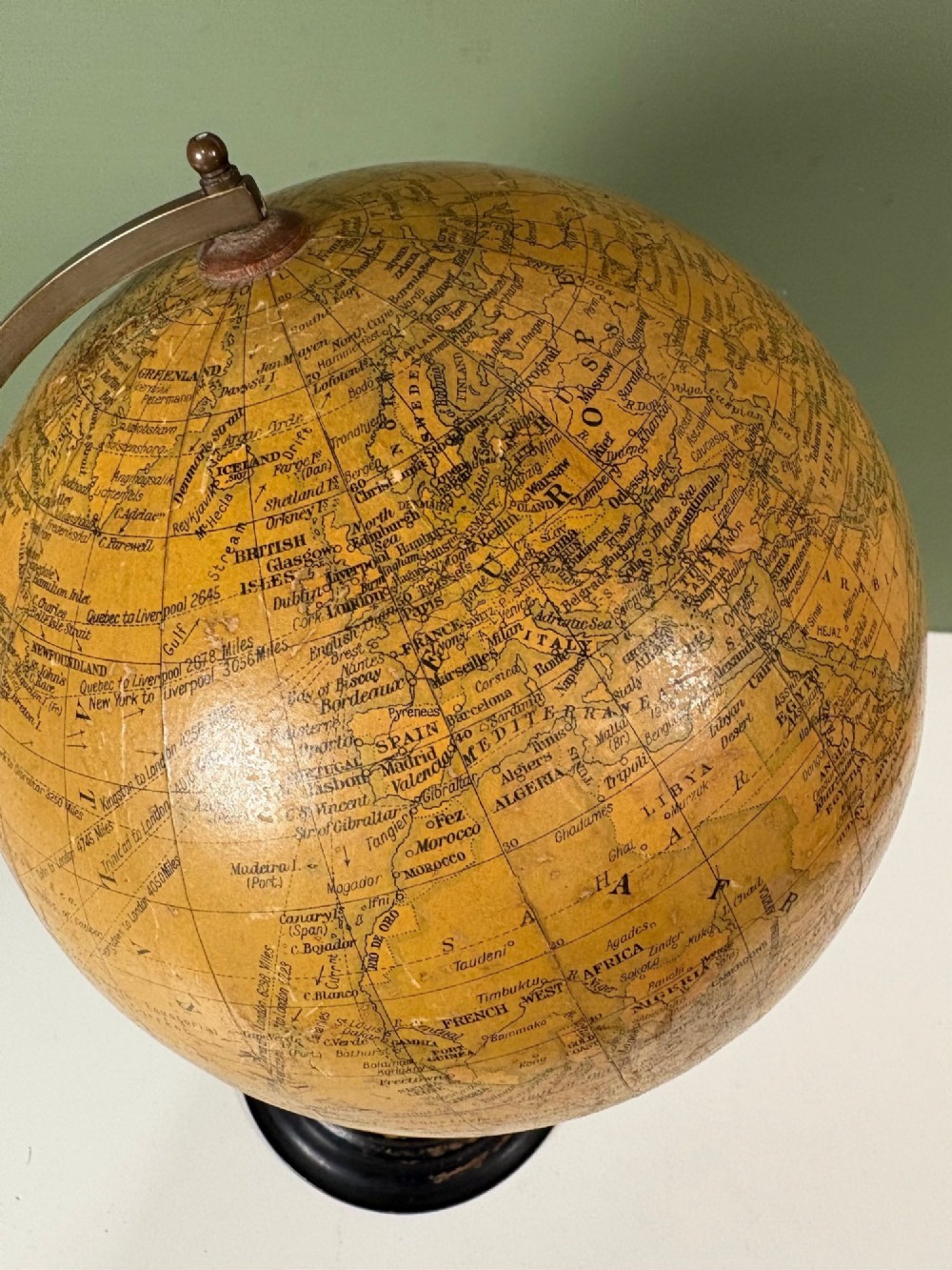 An antique terrestrial table globe with printed paper map gores, a brass semi-meridian arc, and a turned ebonised wooden base. View VI