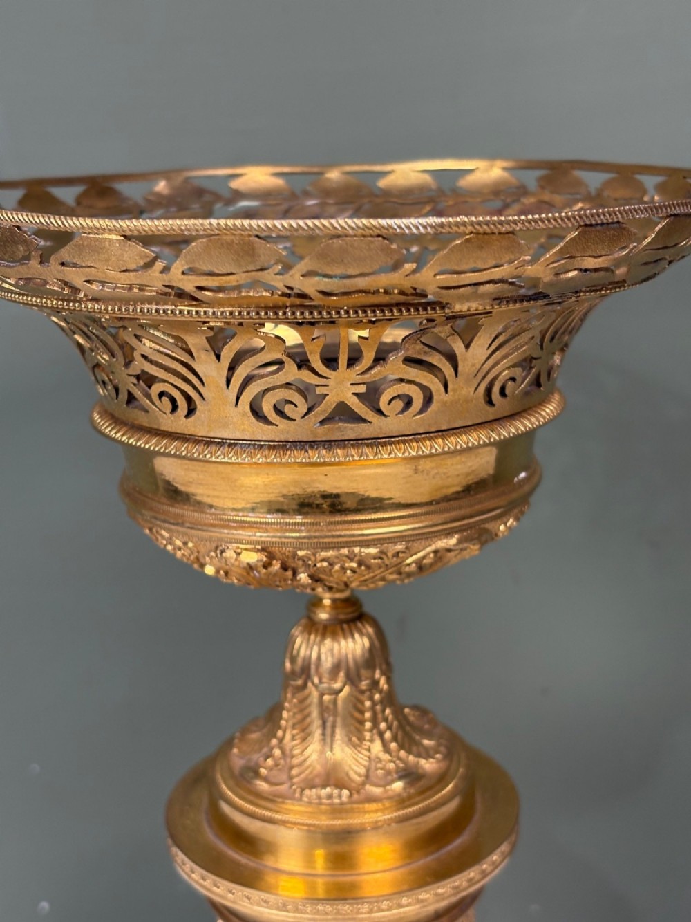 An early 19th-century gilt bronze ormolu vase featuring a pierced filigree flared rim, leaf-moulded bowl, textured pedestal column, and square base. View II