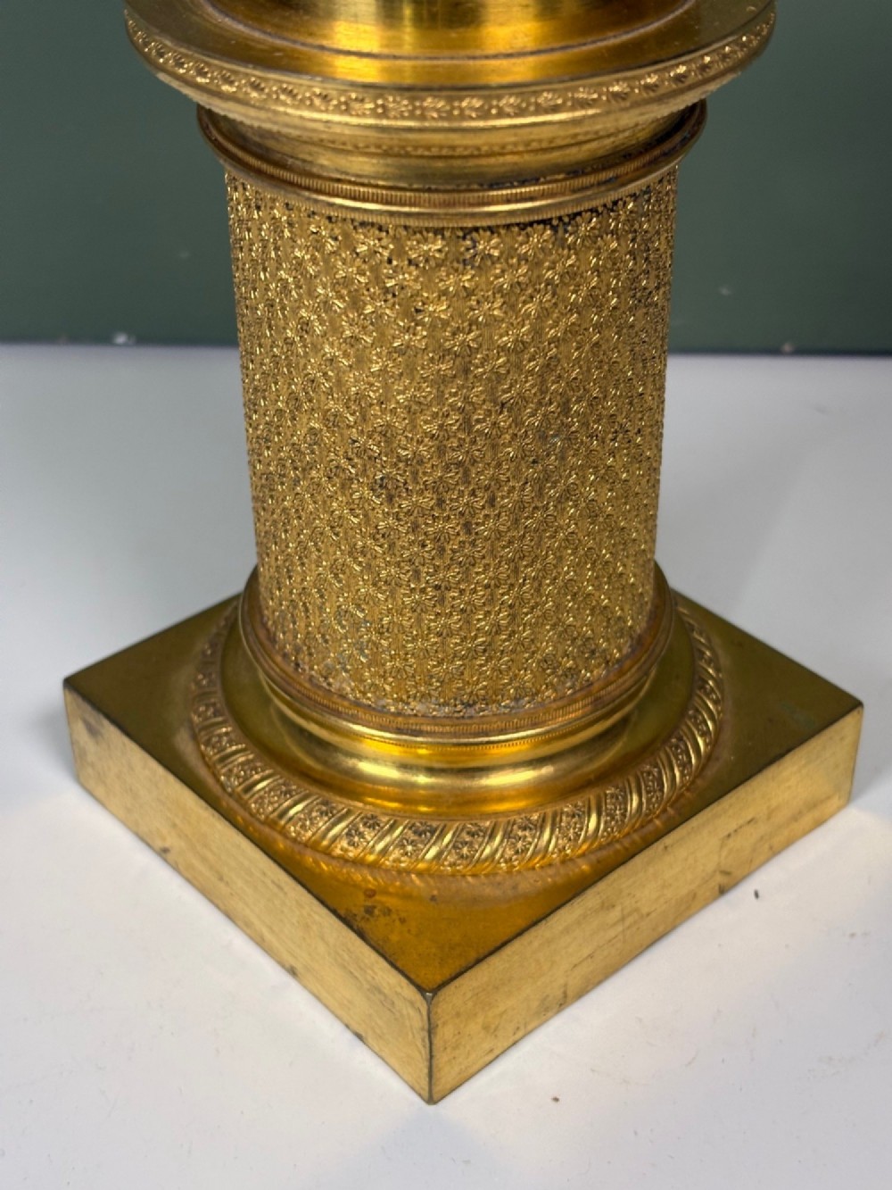 An early 19th-century gilt bronze ormolu vase featuring a pierced filigree flared rim, leaf-moulded bowl, textured pedestal column, and square base. View IV