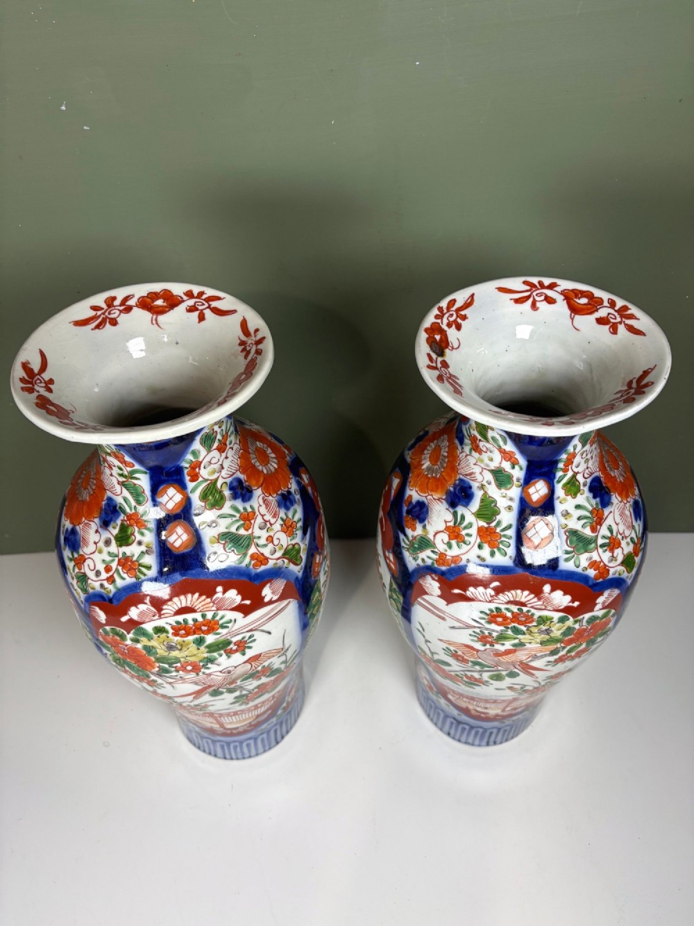 A matching pair of nineteenth-century Japanese Imari porcelain vases featuring hand-painted floral panels, bird motifs, and intricate cobalt blue and iron-red geometric patterns. View V