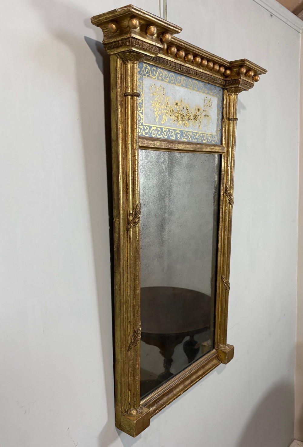 A vertical Regency giltwood pier mirror with fluted side columns, ball-ornamented cornice, and a decorative floral verre eglomise glass panel. View II