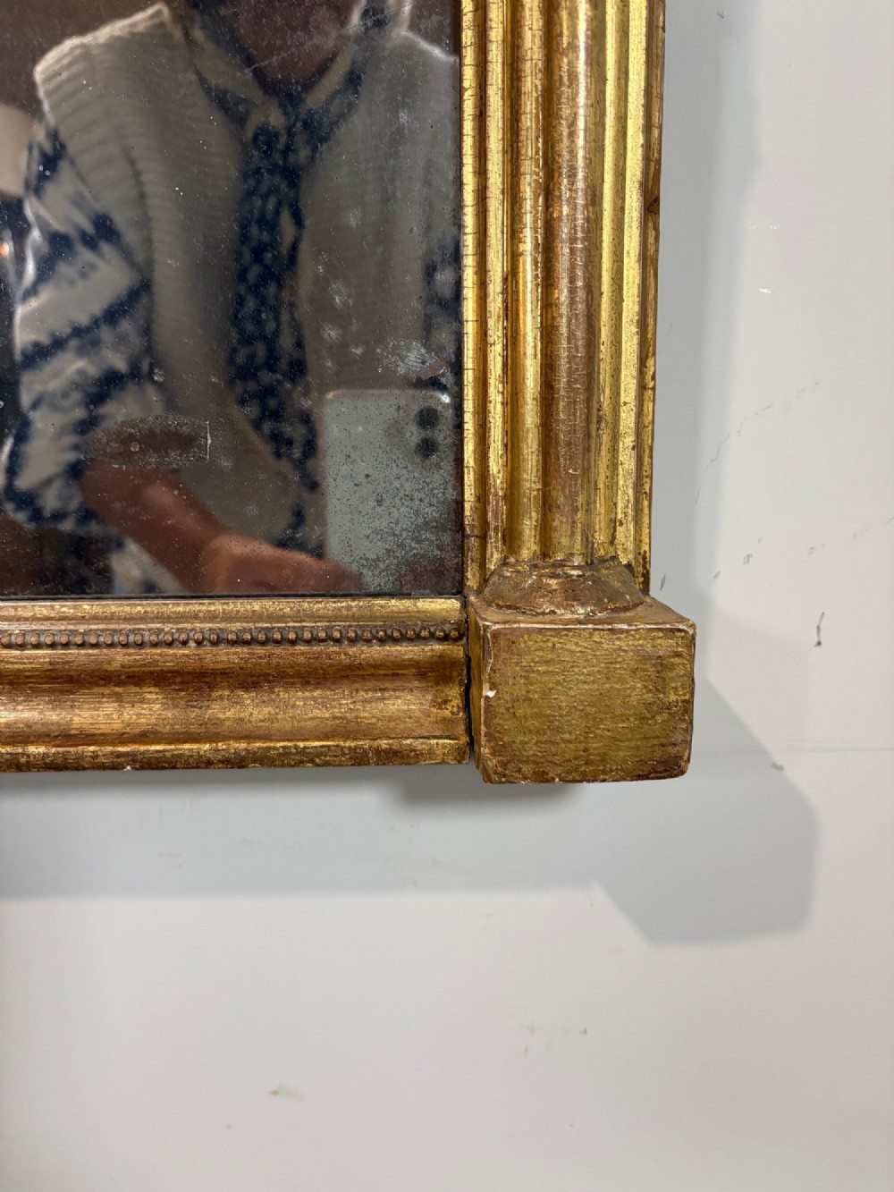 A vertical Regency giltwood pier mirror with fluted side columns, ball-ornamented cornice, and a decorative floral verre eglomise glass panel. View V