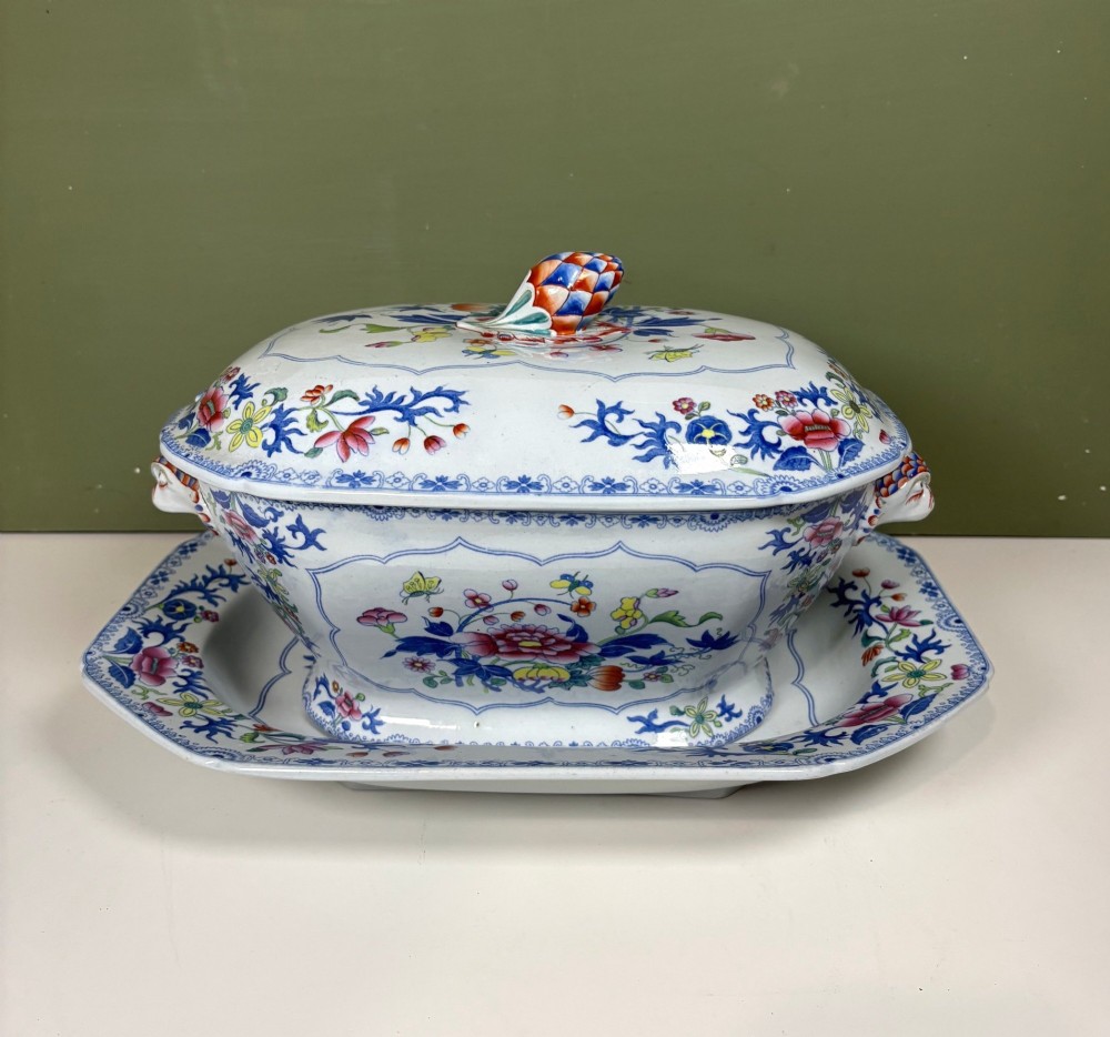 A nineteenth-century ceramic ironstone soup tureen with a patterned lid and matching undertray, decorated in polychrome floral chinoiserie motifs.
