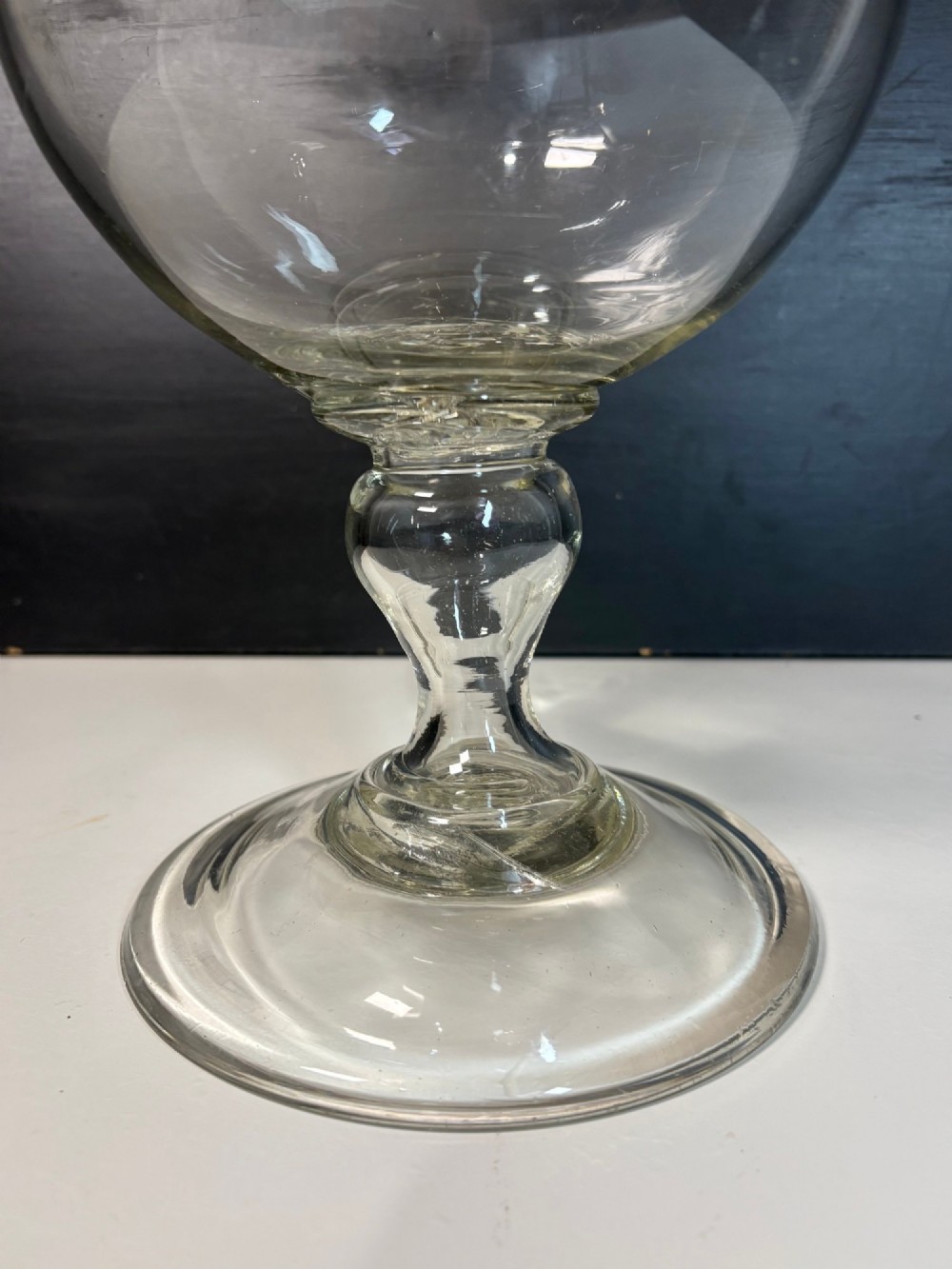 An 18th-century clear hand-blown glass leech jar featuring a wide flared rim, bulbous body, knopped stem, and a wide circular pedestal foot. View VII
