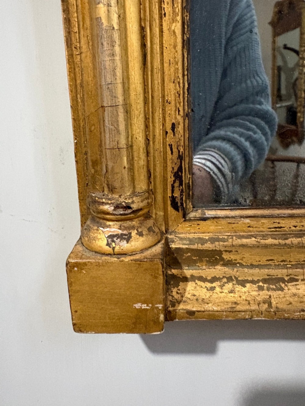 A Regency period giltwood pier glass mirror featuring fluted side columns, a stepped pediment cornice, and an upper verre eglomise glass panel depicting a rural building and landscape. View IV
