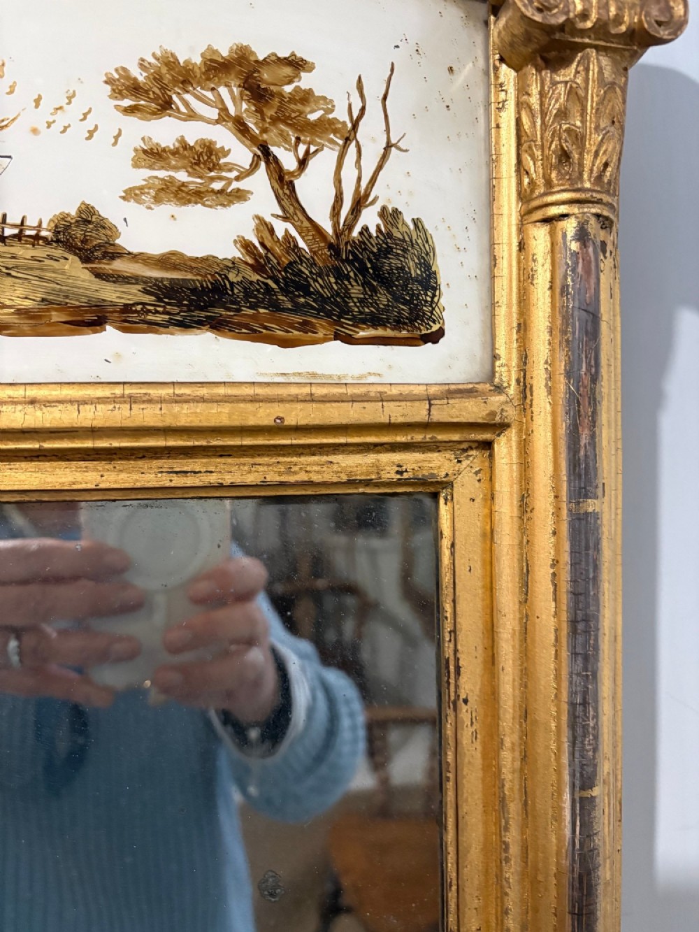 A Regency period giltwood pier glass mirror featuring fluted side columns, a stepped pediment cornice, and an upper verre eglomise glass panel depicting a rural building and landscape. View VI