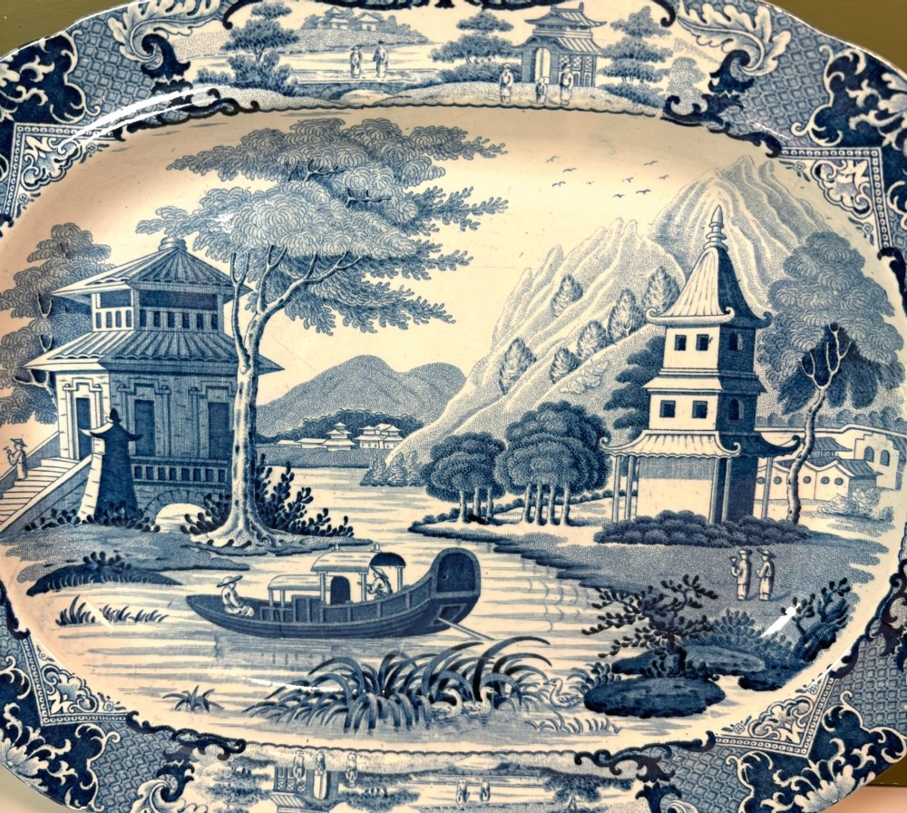 A 19th-century oval blue and white earthenware platter featuring a printed Chinoiserie landscape scene with pagodas, a river boat, and decorative scrollwork borders. View II