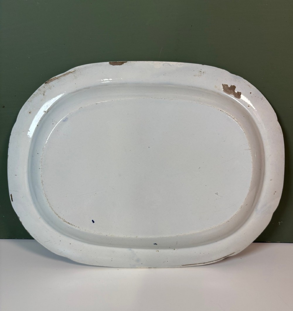 A 19th-century oval blue and white earthenware platter featuring a printed Chinoiserie landscape scene with pagodas, a river boat, and decorative scrollwork borders. View V