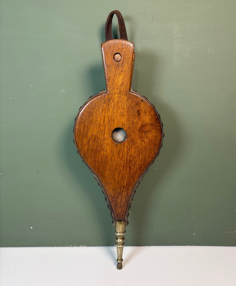 A nineteenth-century oak fire bellows with dark leather trim, brass studding, a leather hanging loop, and a turned brass nozzle. View III