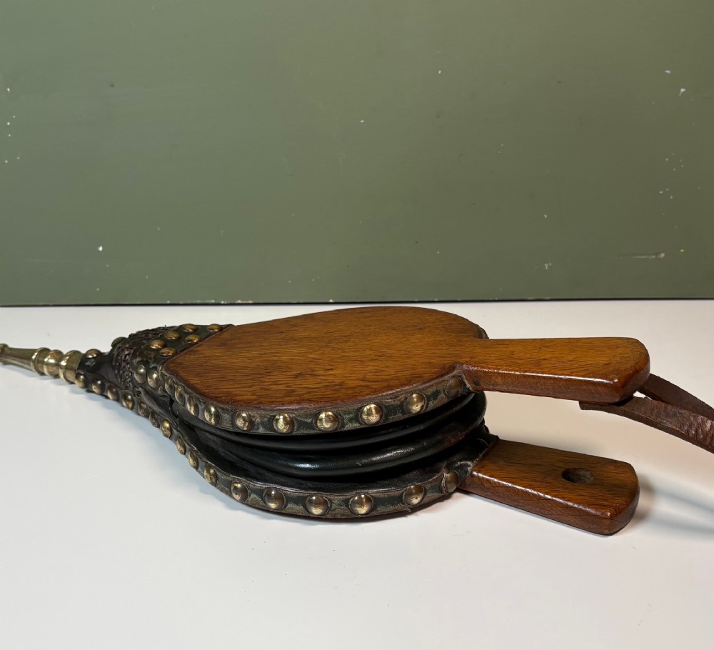 A nineteenth-century oak fire bellows with dark leather trim, brass studding, a leather hanging loop, and a turned brass nozzle. View IV