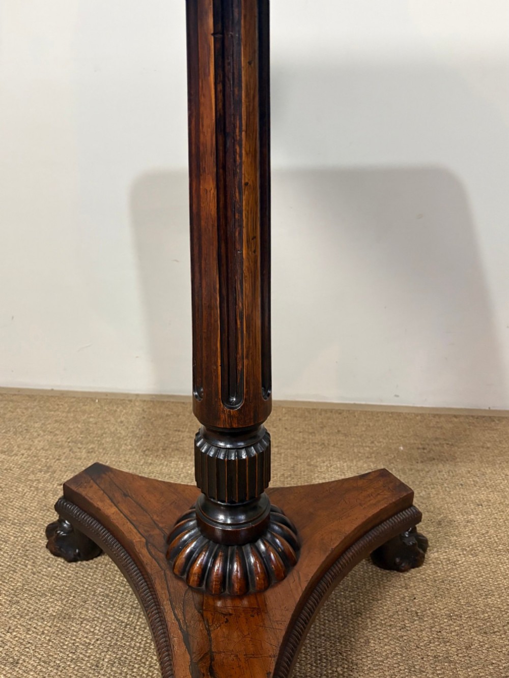 A nineteenth-century rosewood pedestal table featuring a square top, fluted central column, triform base, and carved claw feet. View V