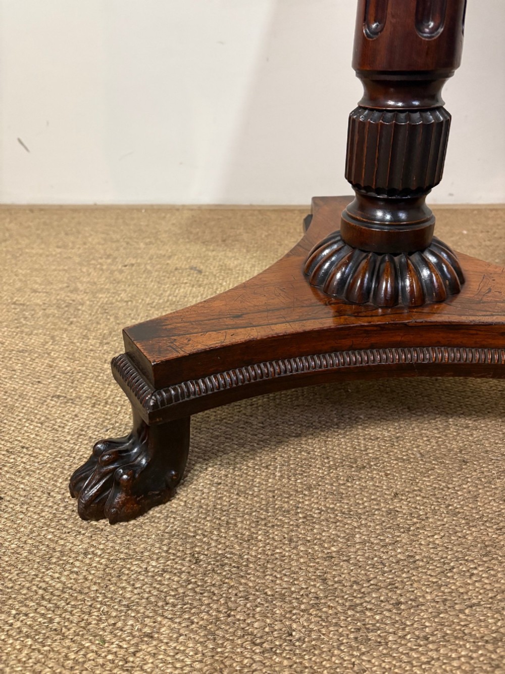 A nineteenth-century rosewood pedestal table featuring a square top, fluted central column, triform base, and carved claw feet. View VI