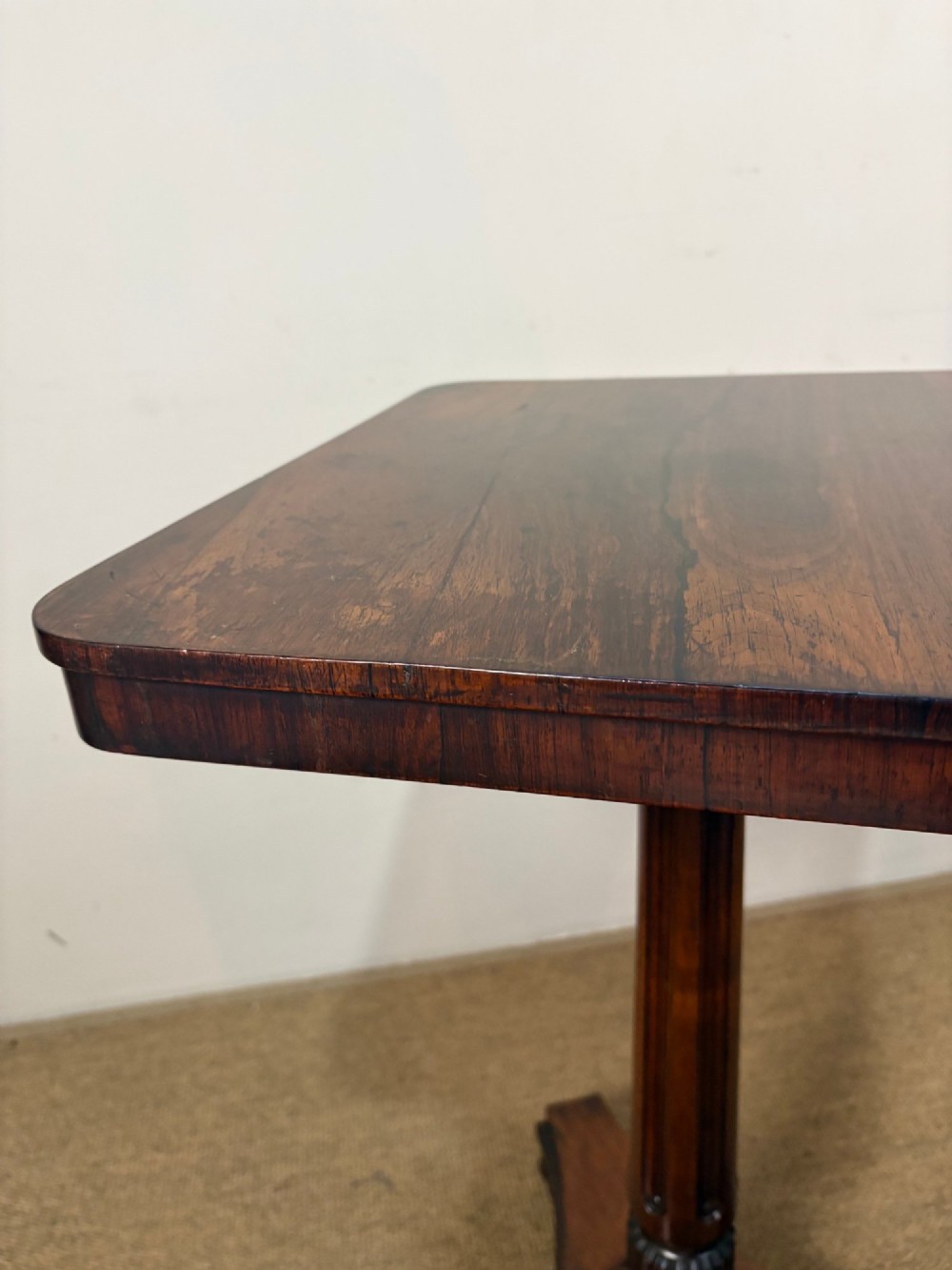 A nineteenth-century rosewood pedestal table featuring a square top, fluted central column, triform base, and carved claw feet. View VII