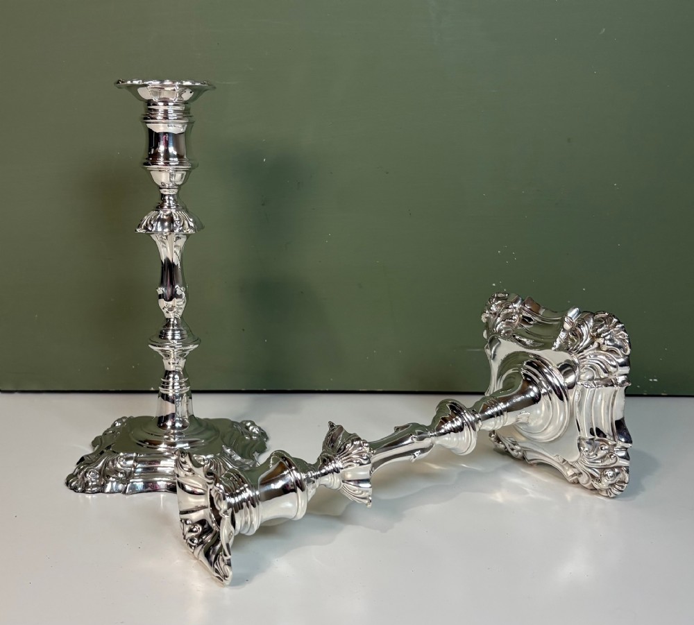 A pair of 19th-century silver candlesticks featuring Rococo style scrollwork, scalloped bases, and knopped stems.