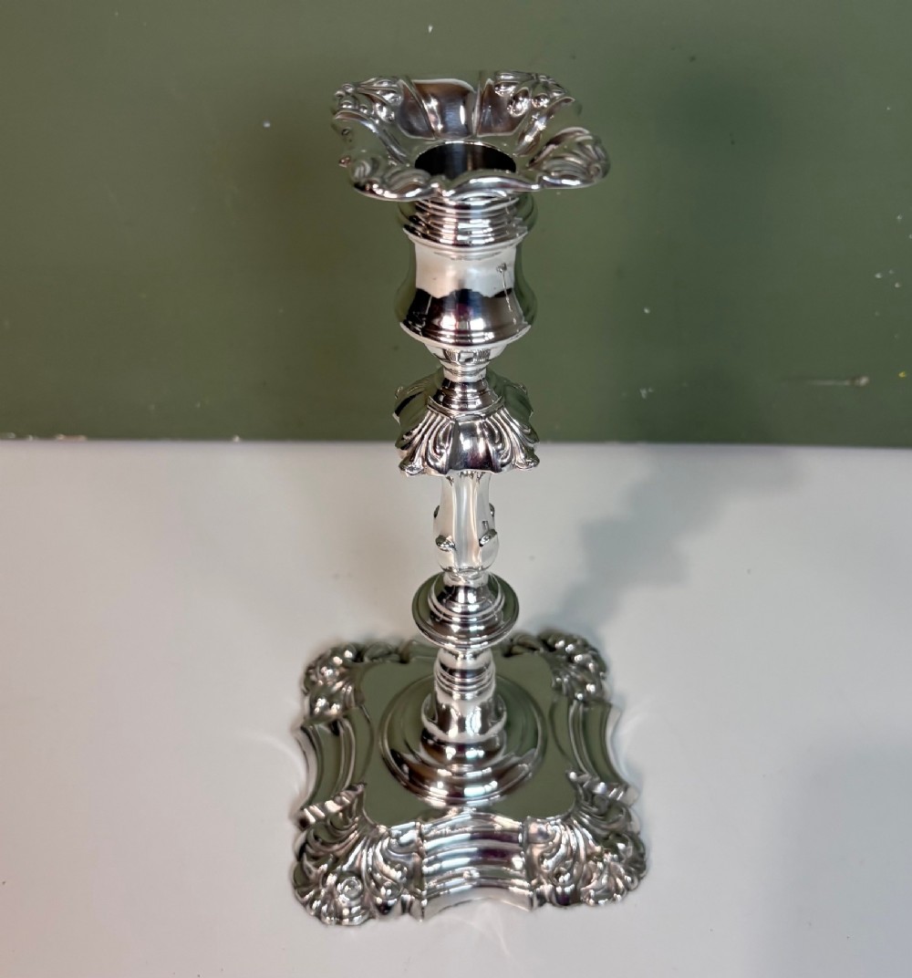 A pair of 19th-century silver candlesticks featuring Rococo style scrollwork, scalloped bases, and knopped stems. View V
