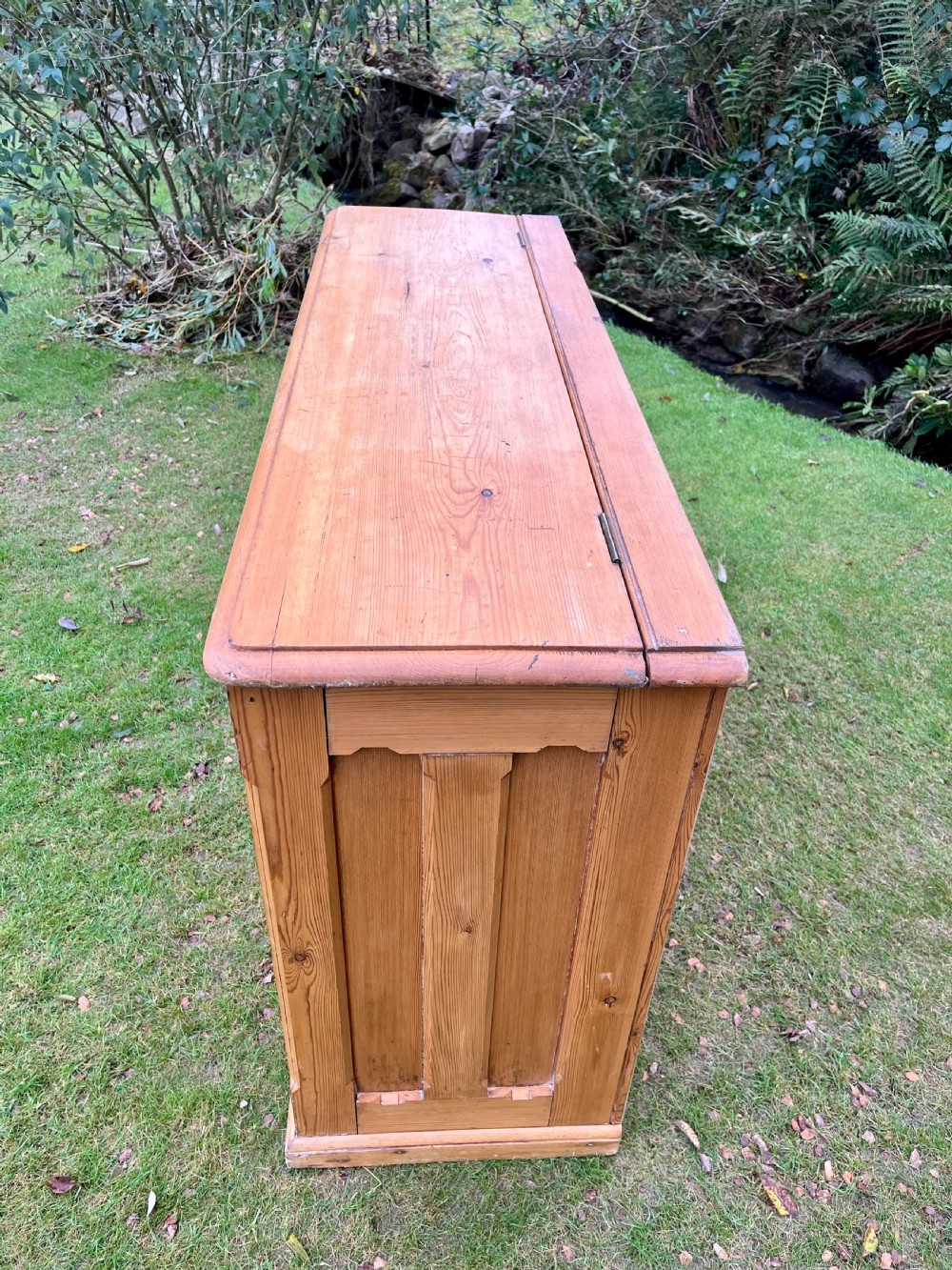 A rectangular antique pine log box featuring vertical timber panelling, a flat top surface, and a solid plinth base. View III