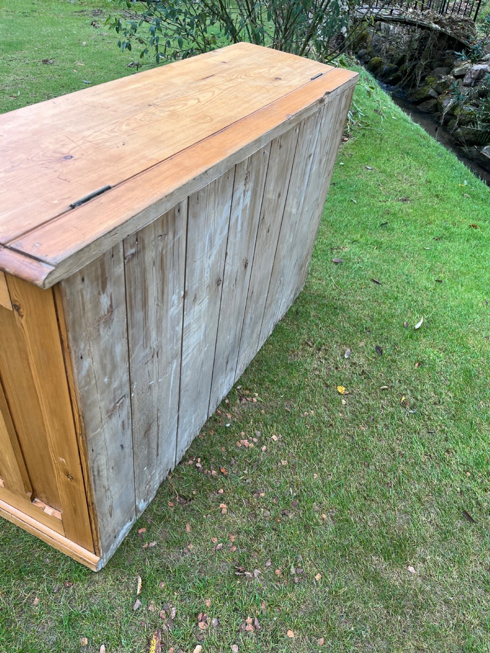 A rectangular antique pine log box featuring vertical timber panelling, a flat top surface, and a solid plinth base. View IV