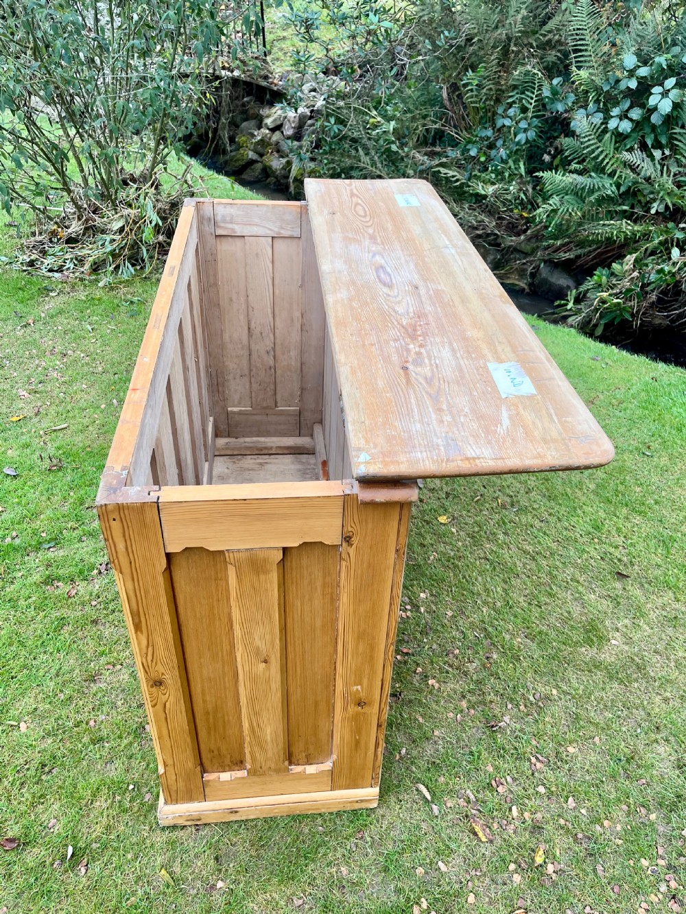 A rectangular antique pine log box featuring vertical timber panelling, a flat top surface, and a solid plinth base. View V