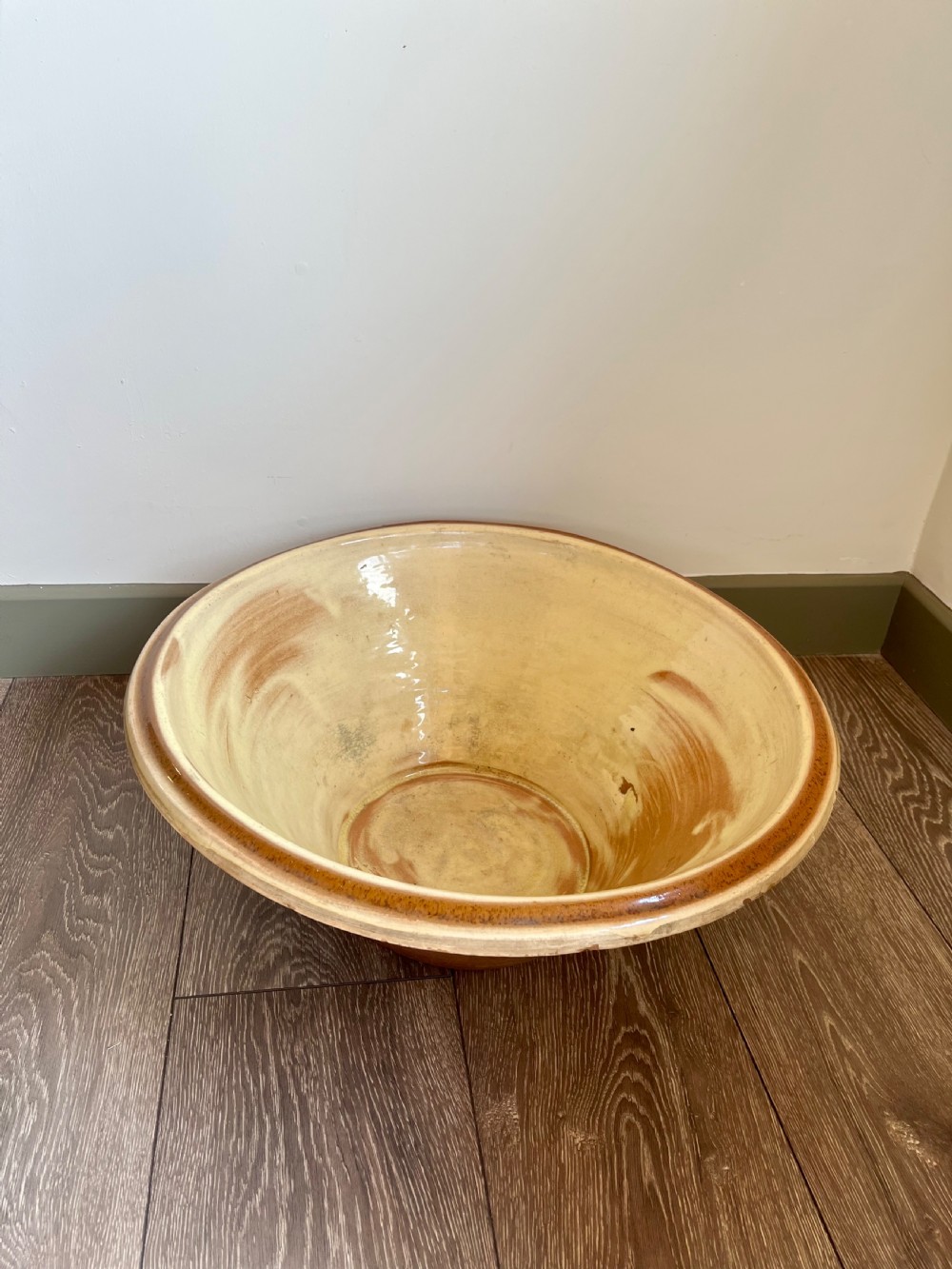A large flared antique terracotta dairy bowl featuring a pale yellow glazed interior and a rounded rolled rim. View V